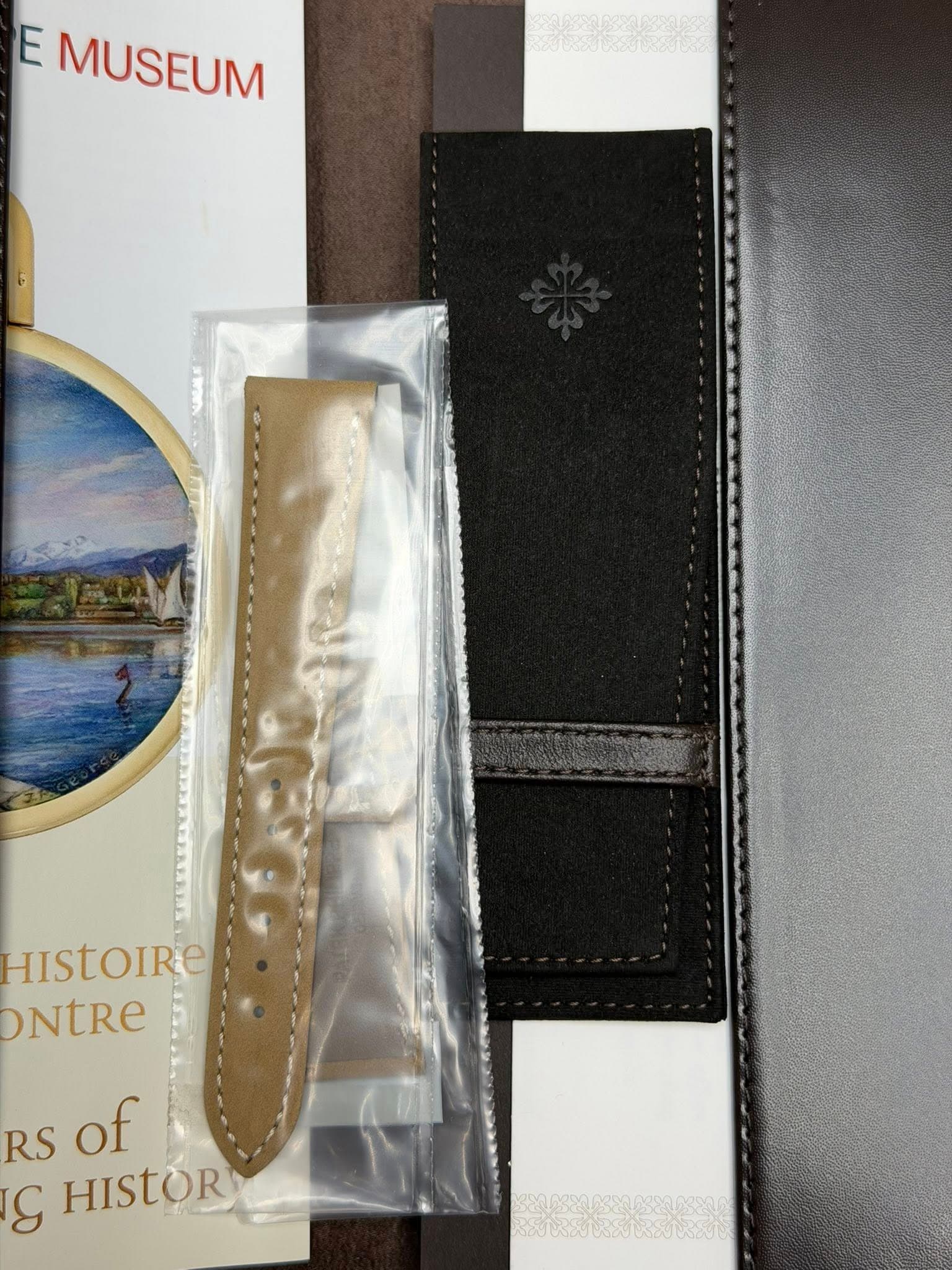 May be an image of wrist watch, leather wallet, leather, saddle-stitched leather and text that says 'E MUSEUM 00005000 HISTOIRe ONTRE RS of S HISTOR'