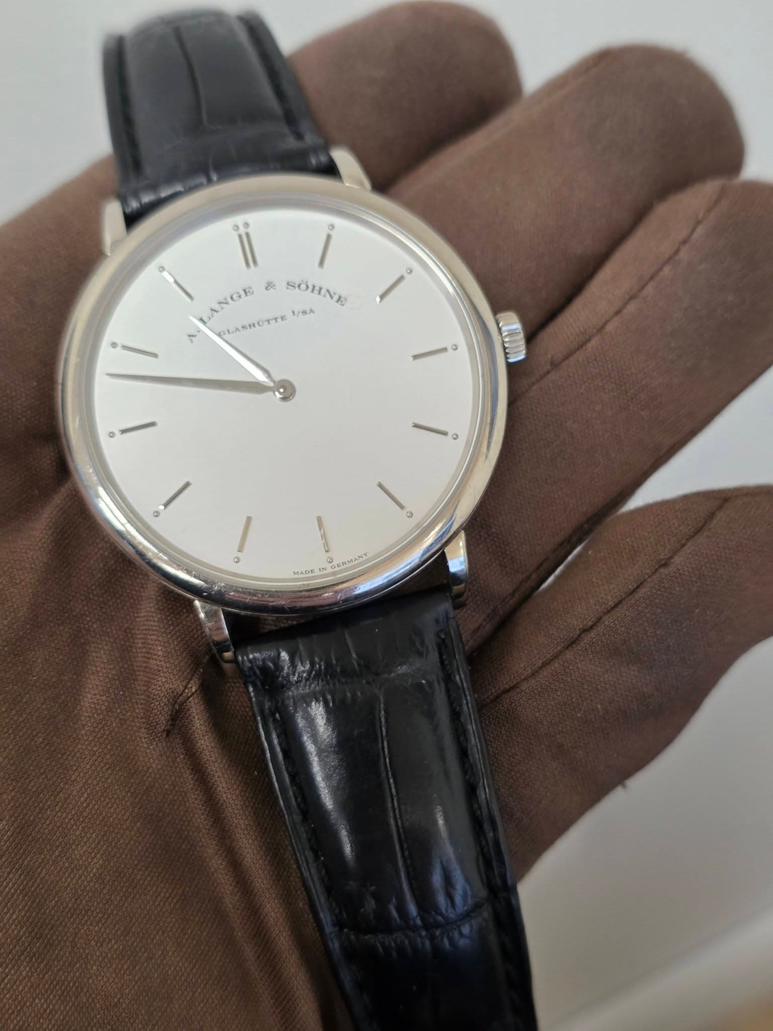 May be an image of wrist watch and text that says '00 o i ANGE & SOHNE N SLASHUTTE SÖHNG V/SA o 0 o 3 / MACK TM GEMMANY ቅበፍአያር'