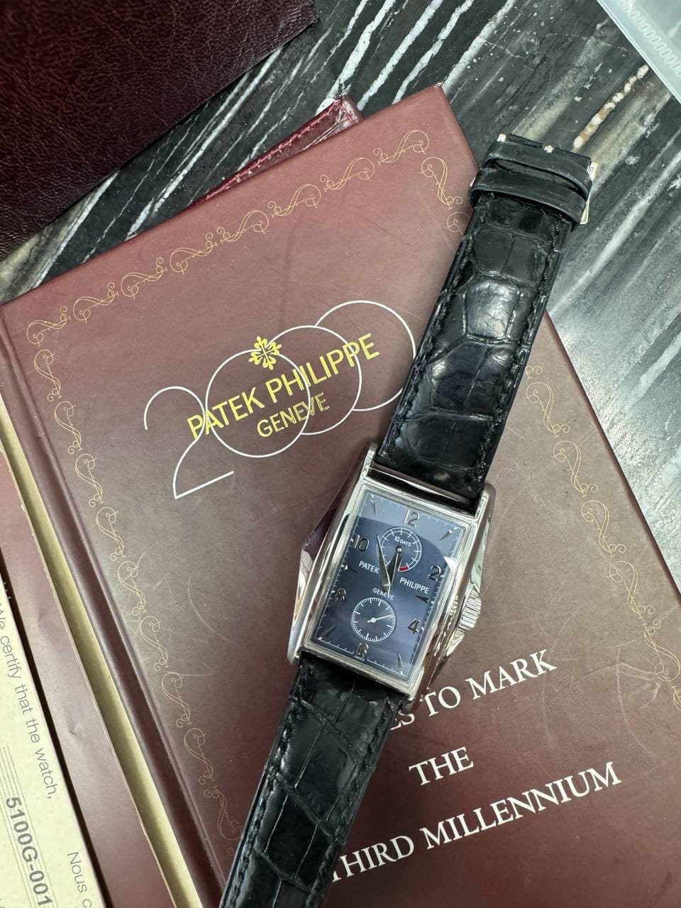 May be an image of leather, wrist watch and text that says 'ATEK 楽 PHILIPPE PHILIPPE GENEVE GENEVE 12 แมิงี PATEK GEaCE PHILIPPE مله certify that the watch, 5100G-00 -00 Nous ro…
