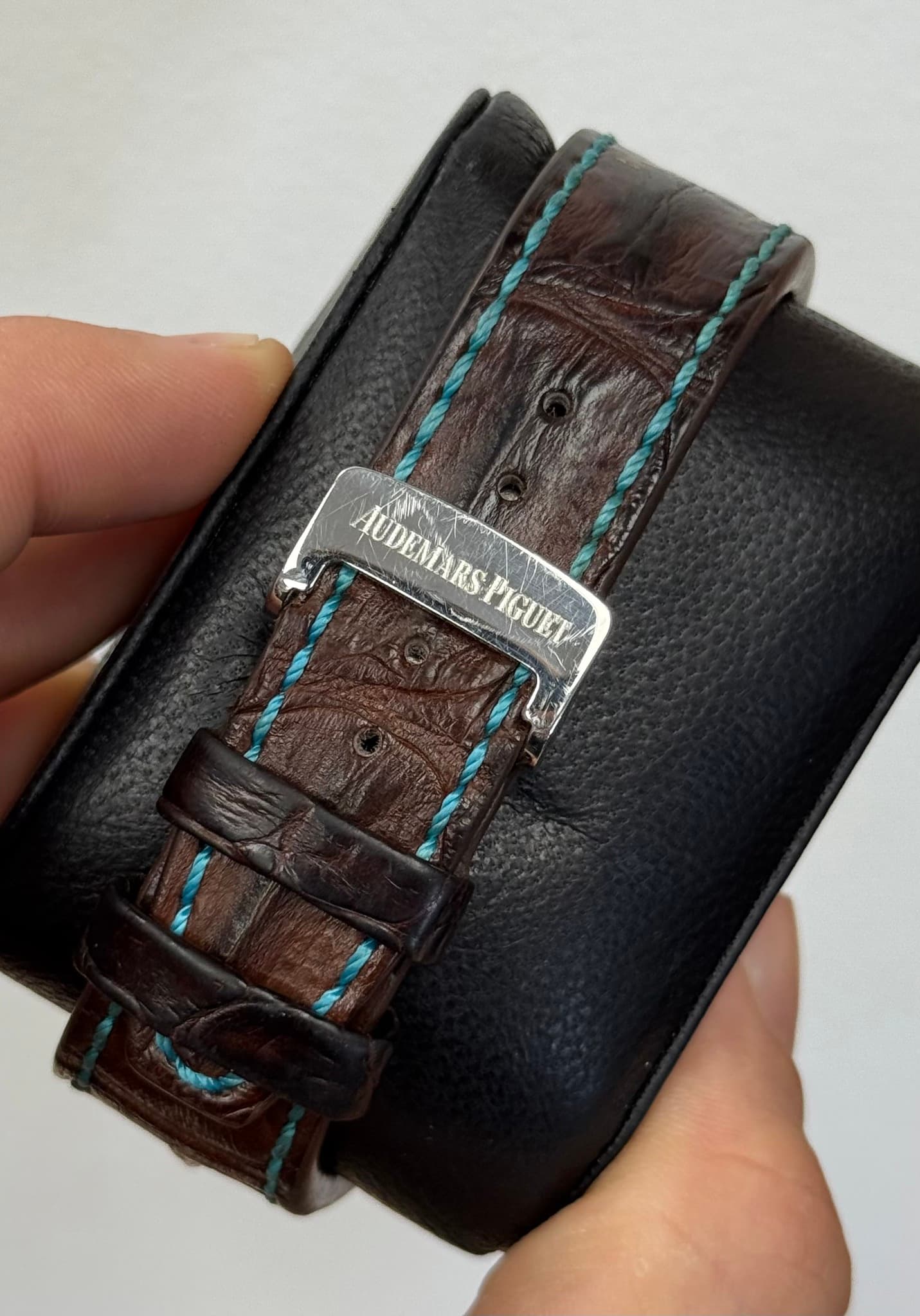 May be an image of leather wallet, wrist watch, saddle-stitched leather, leather and text