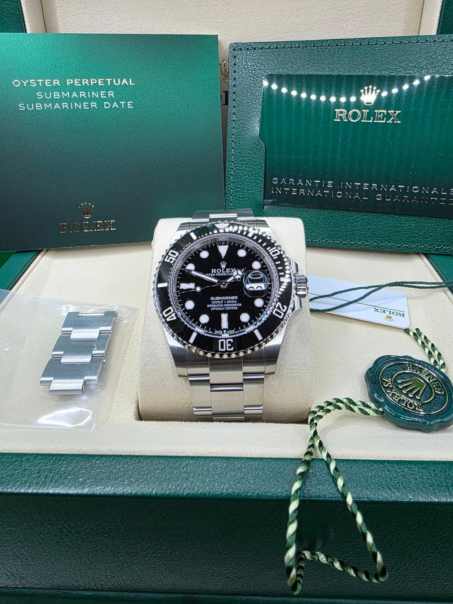 May be an image of wrist watch and text that says 'OYSTER PERPETUAL SUBMARINER SUBMARINER DATE li- ROLEX 屋 WAPGA GARANTIE INTERNATIONA AINTERNATI 50 10, ROLE ROLEY ០០០០០ C…