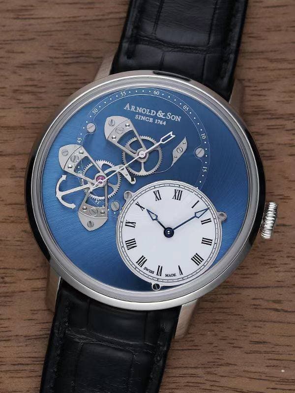 May be an image of wrist watch and text that says '50 55 60 ARNOLD 1764 SLSON 05 SINCE ممدف 10 2 م m SI MaW XI XII II II SWIS SWISS () III MADE'
