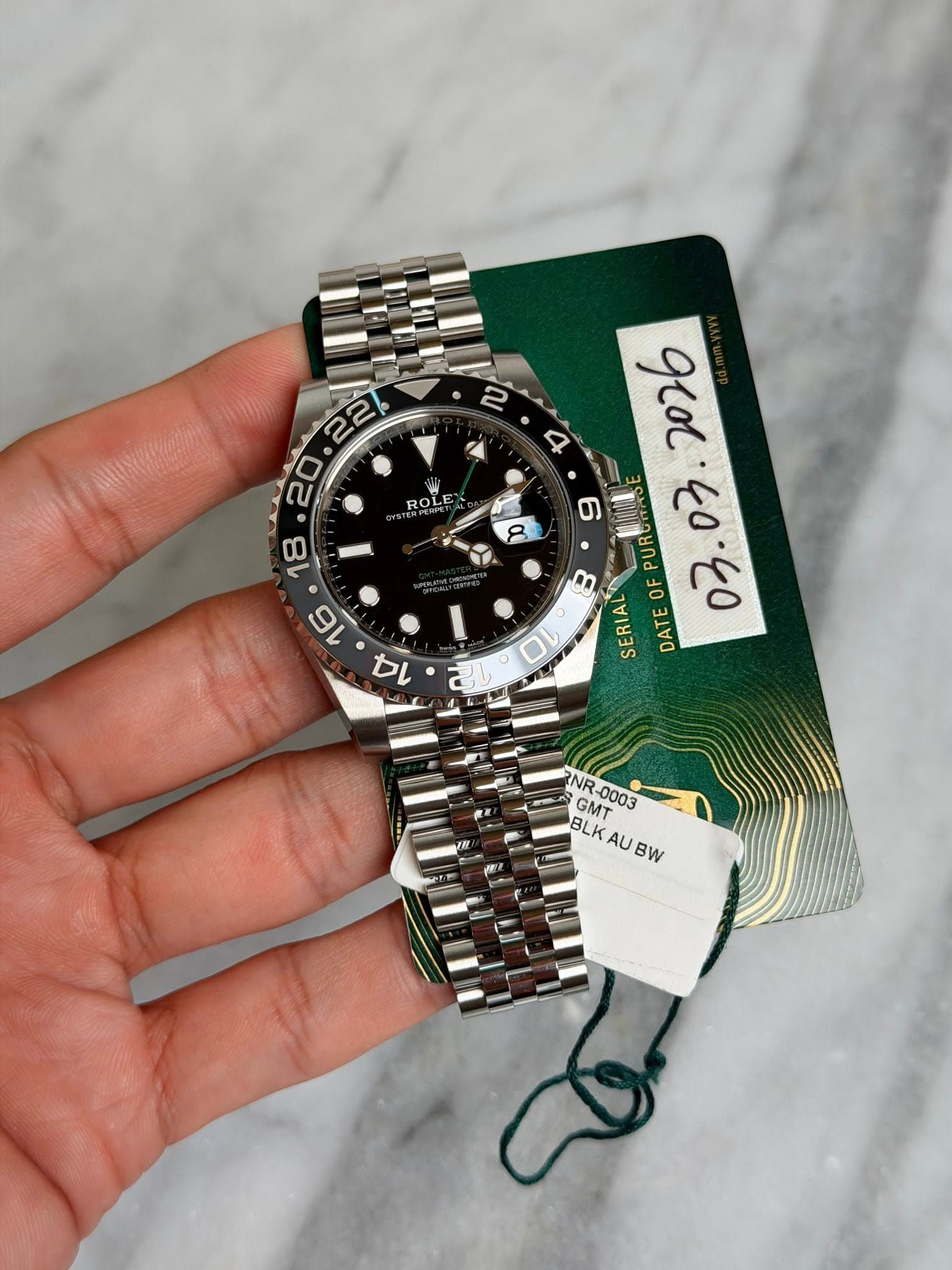 May be an image of wrist watch and text that says ' ROLE ROL اه ን 03. PUR B OF 10 SERIAL DATE NR V NF BLKAUBW GMT -0003 BLK AU BW'