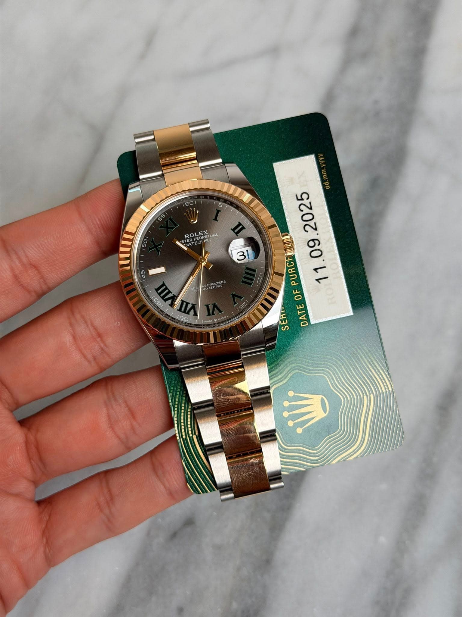 May be an image of wrist watch and text that says 'ROLEX LEX TUAS 31 Opi 2025 PURCH OF RO SERT DATE GC'