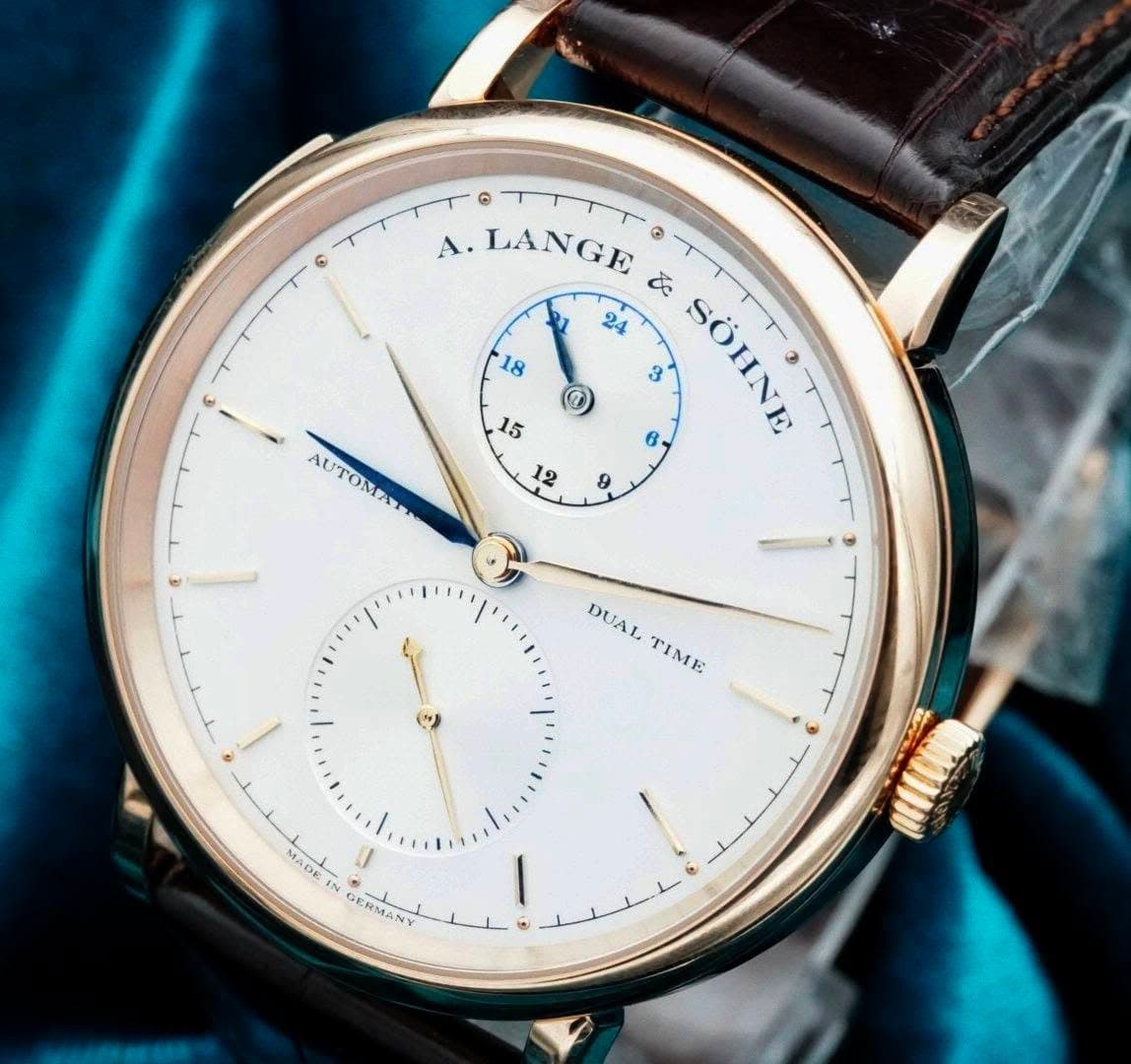 May be an image of wrist watch and text that says '၈ 18 ဓ A. LANGE よ 24 3 6, SÔIN SOHNE 9 15 12 AUTOMA AUTOMAT TOM DUAL TIME MADE GERMANY سلم'