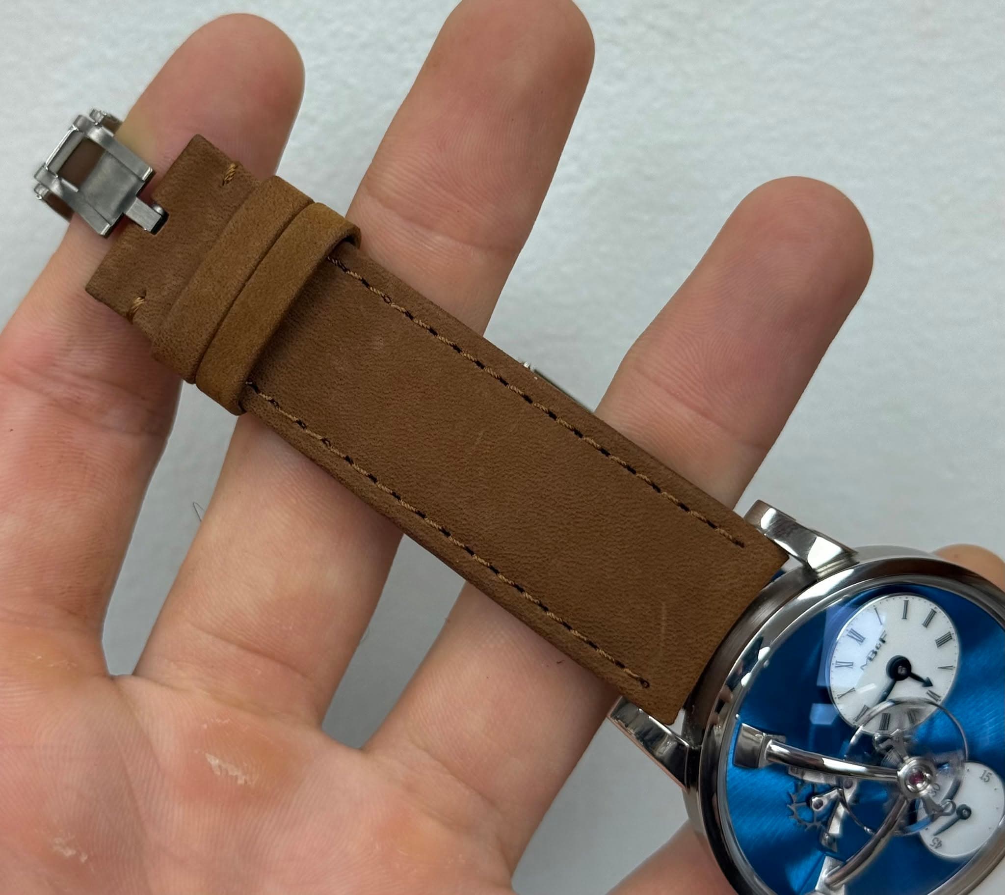 May be an image of wrist watch, leather and text