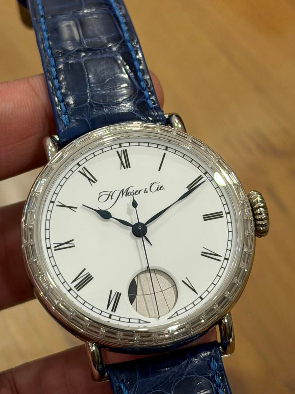 May be an image of wrist watch and text that says 'XII XI HMoser&Cie. Tie. X II IX IV I VII'