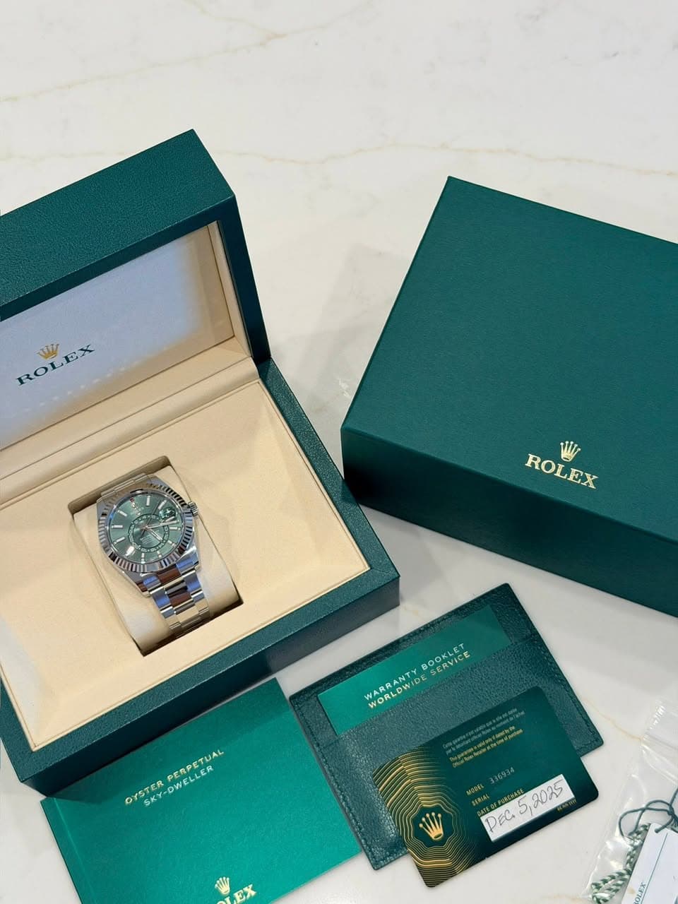 May be an image of wrist watch and text that says 'KOLBX RO ROLEX W WUMI IL ROLEX ROLEX BOOKLET OREET SERVICE WARRANT WORLDW WORLDWIDE WIDE PERPETUAL DWELLER OYSTER YSTERPERPET…